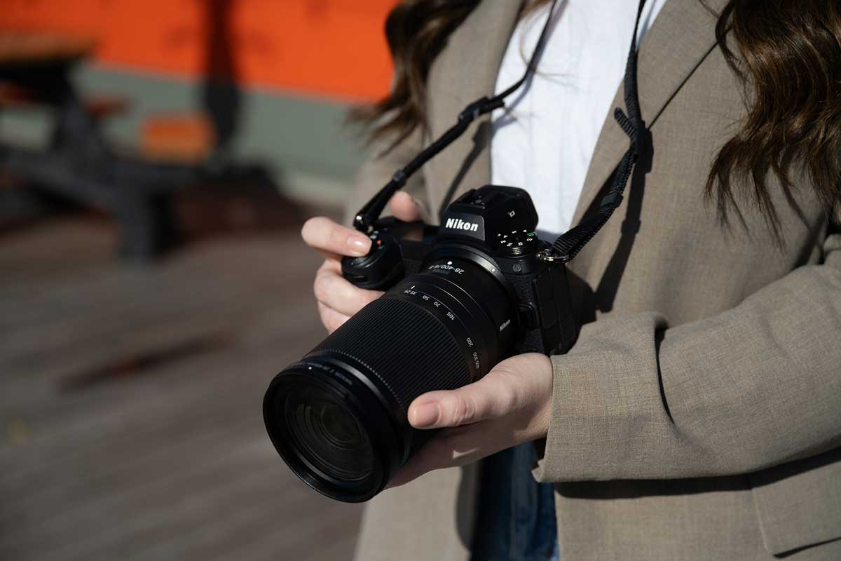 Nikkor Z 28-400mm superzoom lens attached to Nikon body photographed outside outside in sunny conditions, held by a woman