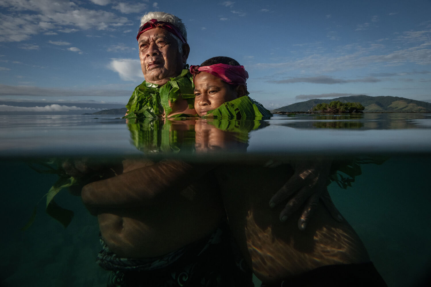 An elder and a child, half-submerged in water, in a portrait of resilience and adaptation in a changing climate.