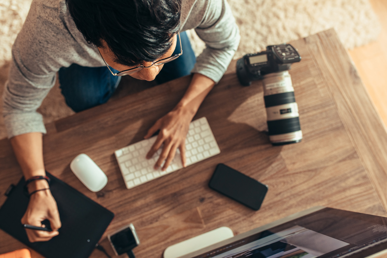 Overhead view of photographer editing photos at his studio. Photographer editing photos after a photo shoot using graphic tablet and stylus pen. Focus on photographer.