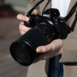 Close up of person holding a nikon camera with superzoom lens attached