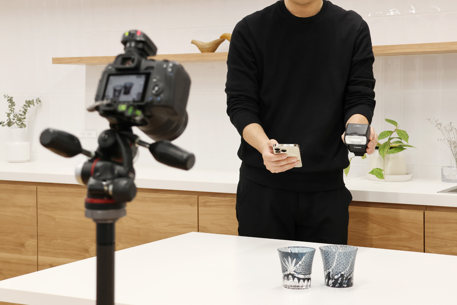 Lifestyle phot of photographer using his smartphone to control Canon Speedlight EL-10 in a kitchen shoot.