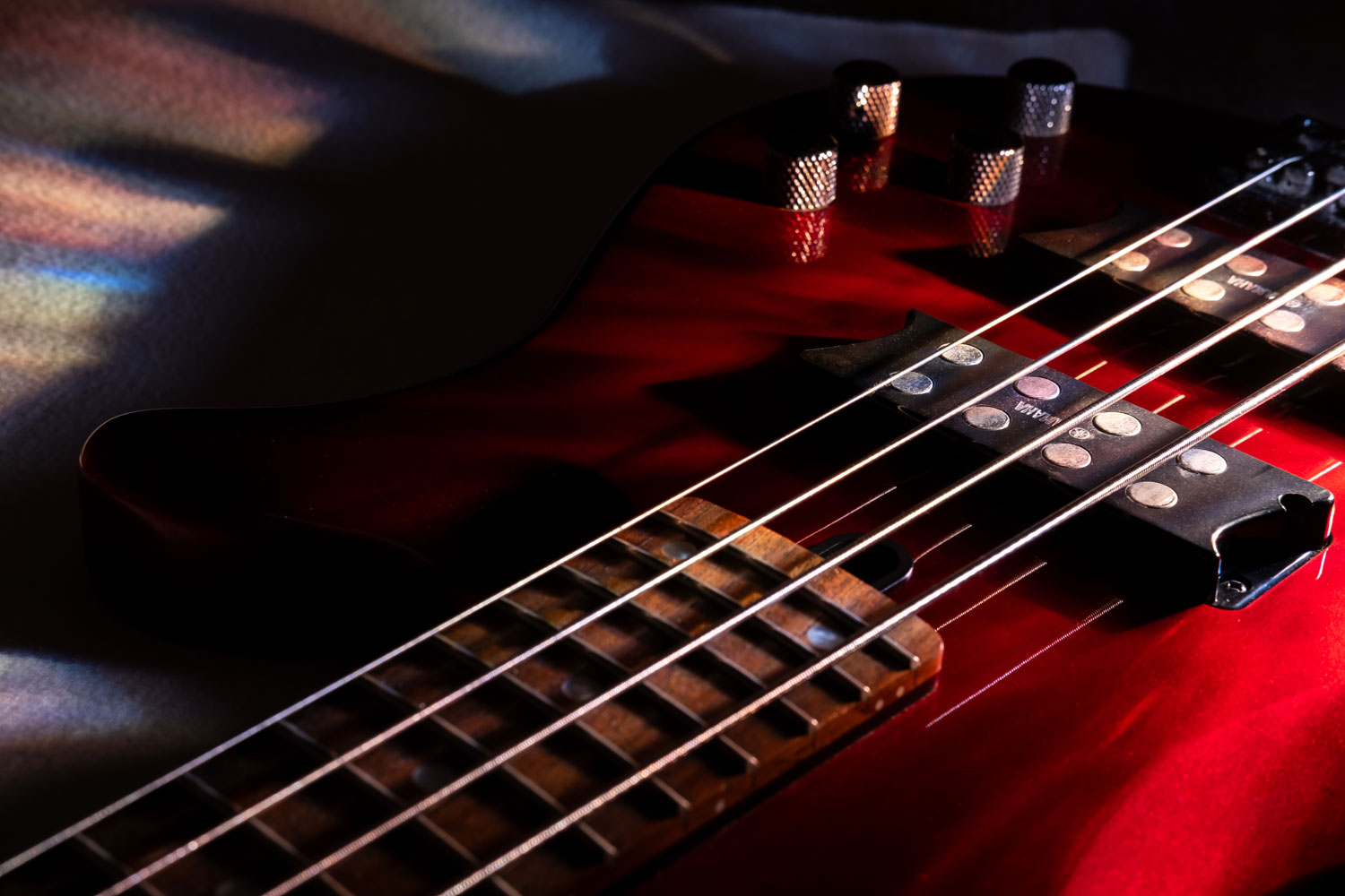 Image of bass guitar colourfully lit with patterned lens